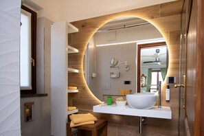 Un baño moderno con un espejo grande, un lavamanos blanco y un tocador de madera.