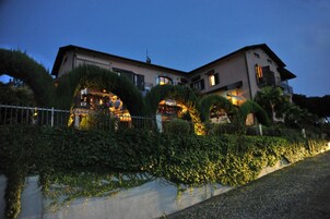 Un edificio a due piani con un balcone e una zona salotto esterna coperta.