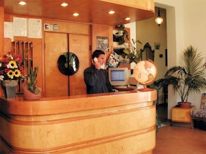 A reception desk with a wooden finish, a globe, and a computer monitor. - Hotel Parma Mare (Massa)