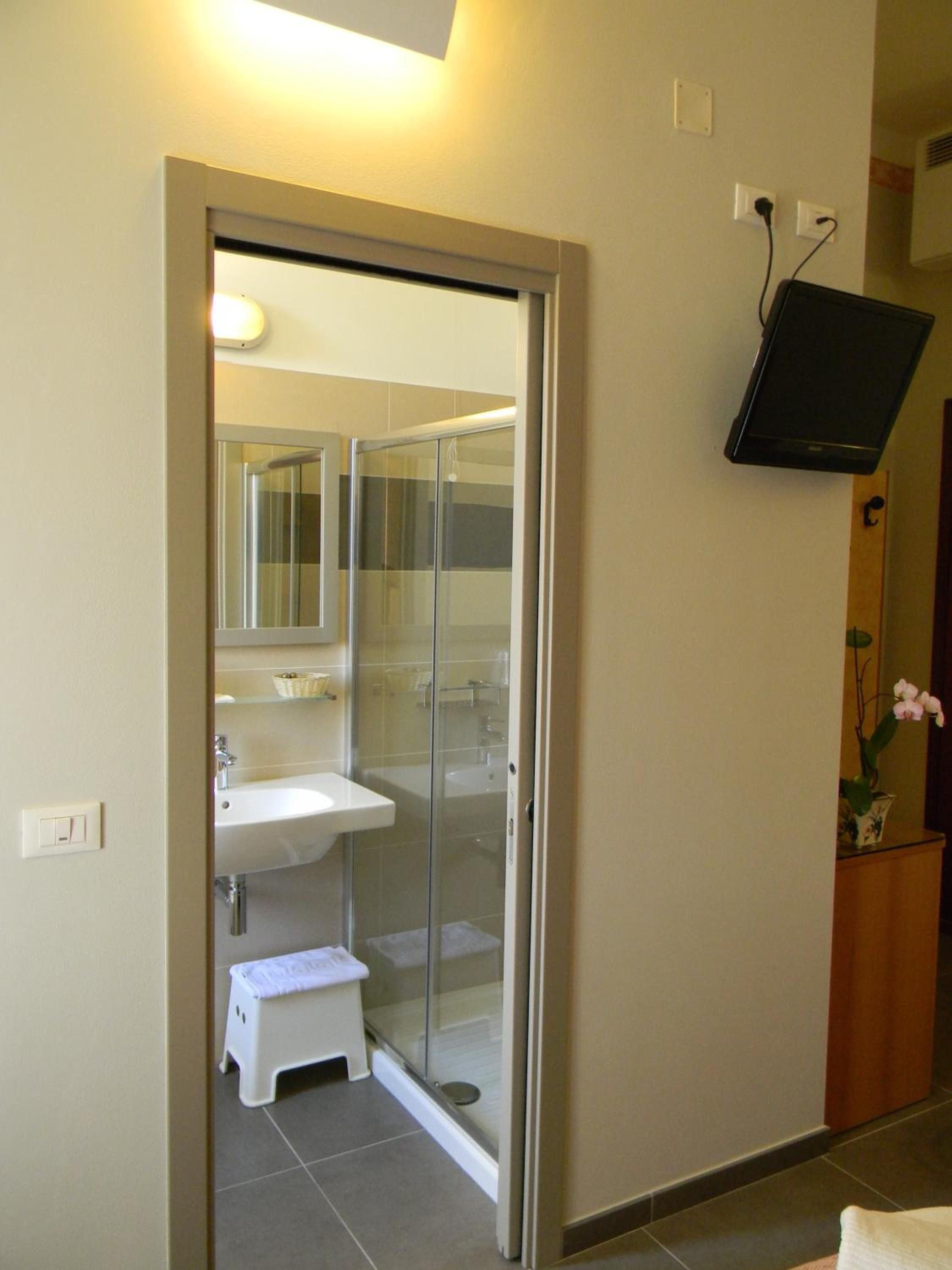 Une salle de bain avec une douche à parois de verre, un lavabo blanc et un petit tabouret.