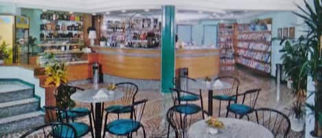 Un espacio interior amplio con varias mesas y sillas, una barra central y estantes llenos de distintos artículos.