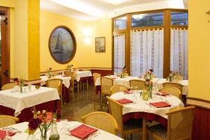 Un comedor con mesas redondas, sillas de mimbre y paredes amarillas.