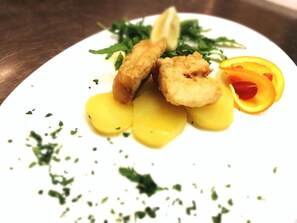 Un plato con alimentos fritos, una rodaja de naranja y guarnición verde.