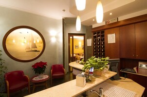 A reception area with a round mirror, red chairs, a potted plant, a reception desk, and a wall-mounted display case.