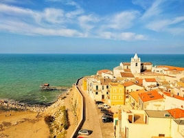 A coastal town with buildings along the waterfront, a promenade, and a clear view of the sea.
