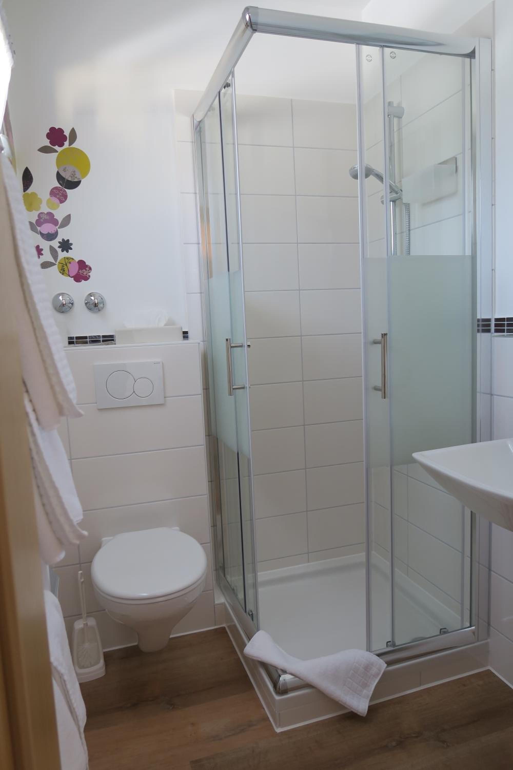 Ein Badezimmer mit einer Duschkabine, einer Toilette und einem Waschbecken.