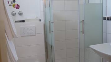 Ein Badezimmer mit einer Duschkabine, einer Toilette und einem Waschbecken.
