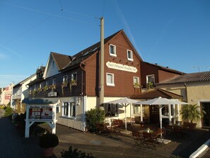 Hotel med udendørs siddepladser og et skilt, der angiver, at det er en restaurant.