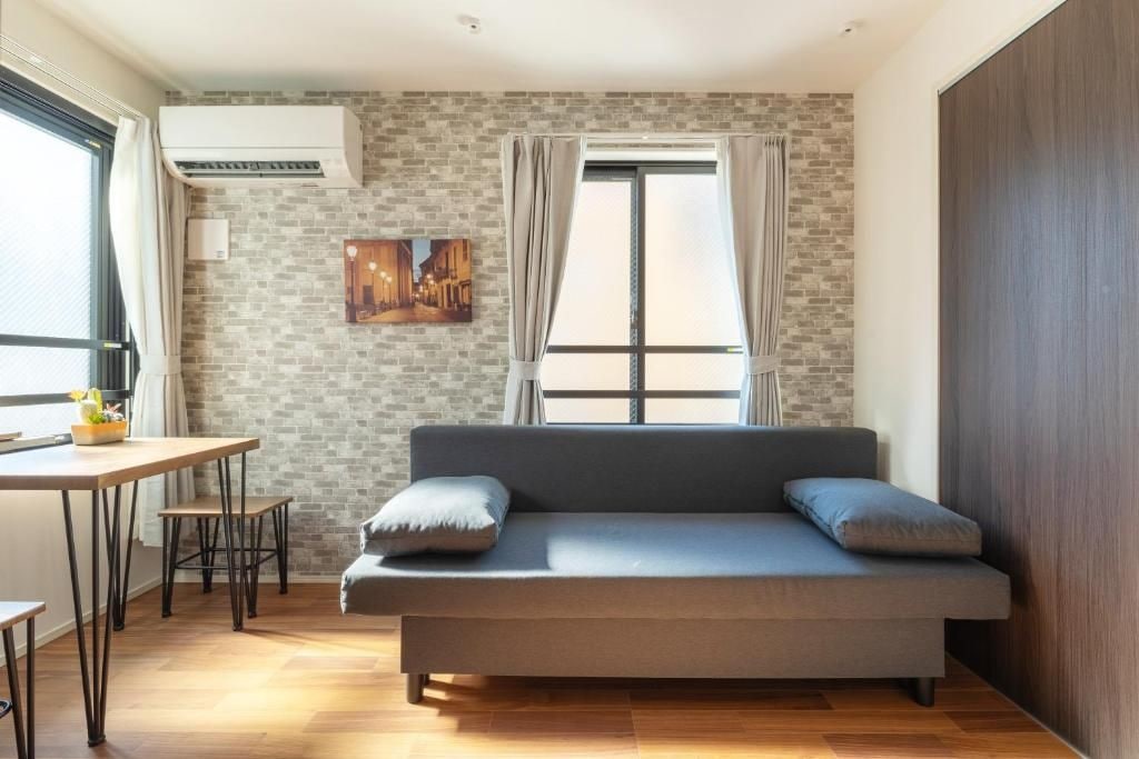 Habitació moderna amb un sofà, una taula petita i una finestra amb cortines.