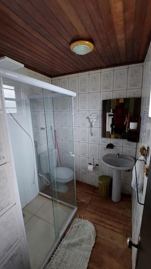 A bathroom with a glass shower enclosure, a toilet, a sink, and a mirror. - Pousada Chalés Da Felicidade (Itu)