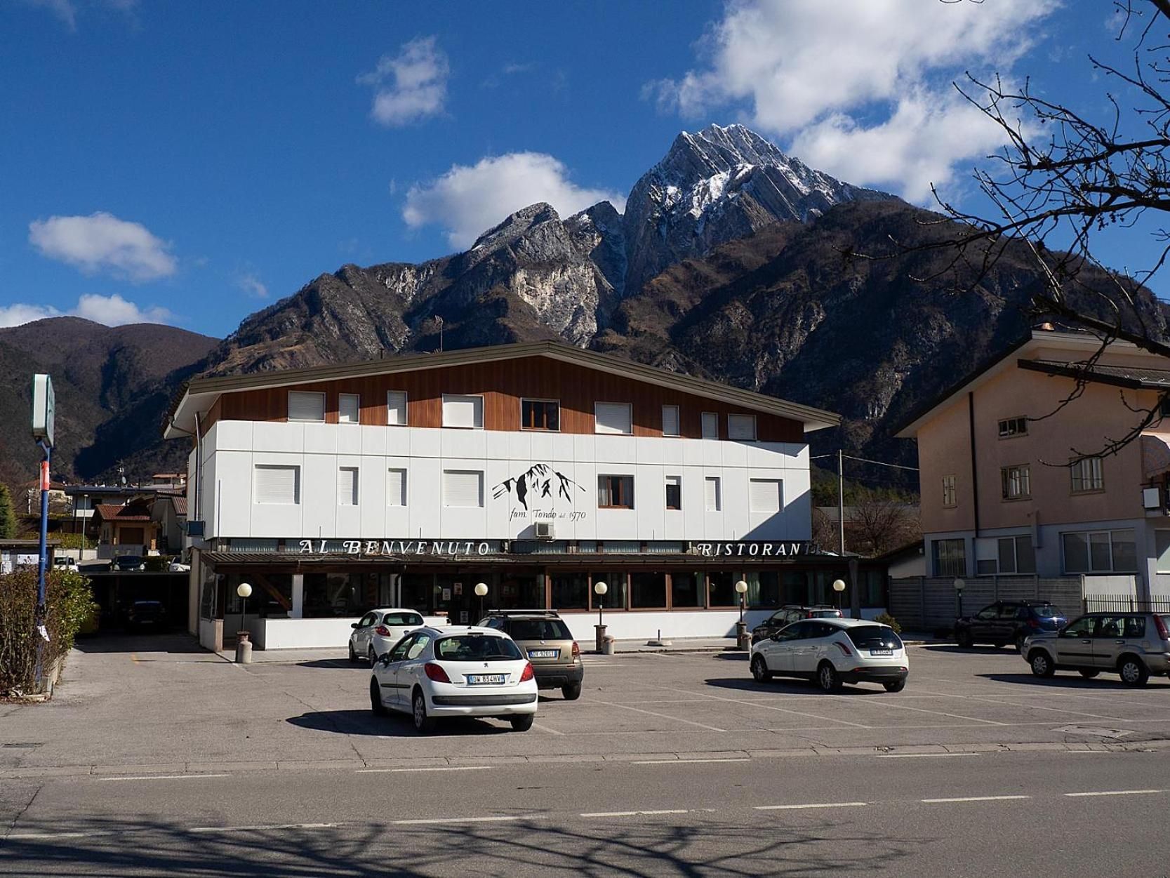 Un edificio con un letrero de restaurante, autos estacionados y montañas al fondo.