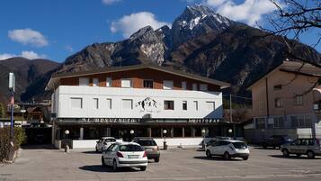 A building with a restaurant sign, parked cars, and mountains in the background.