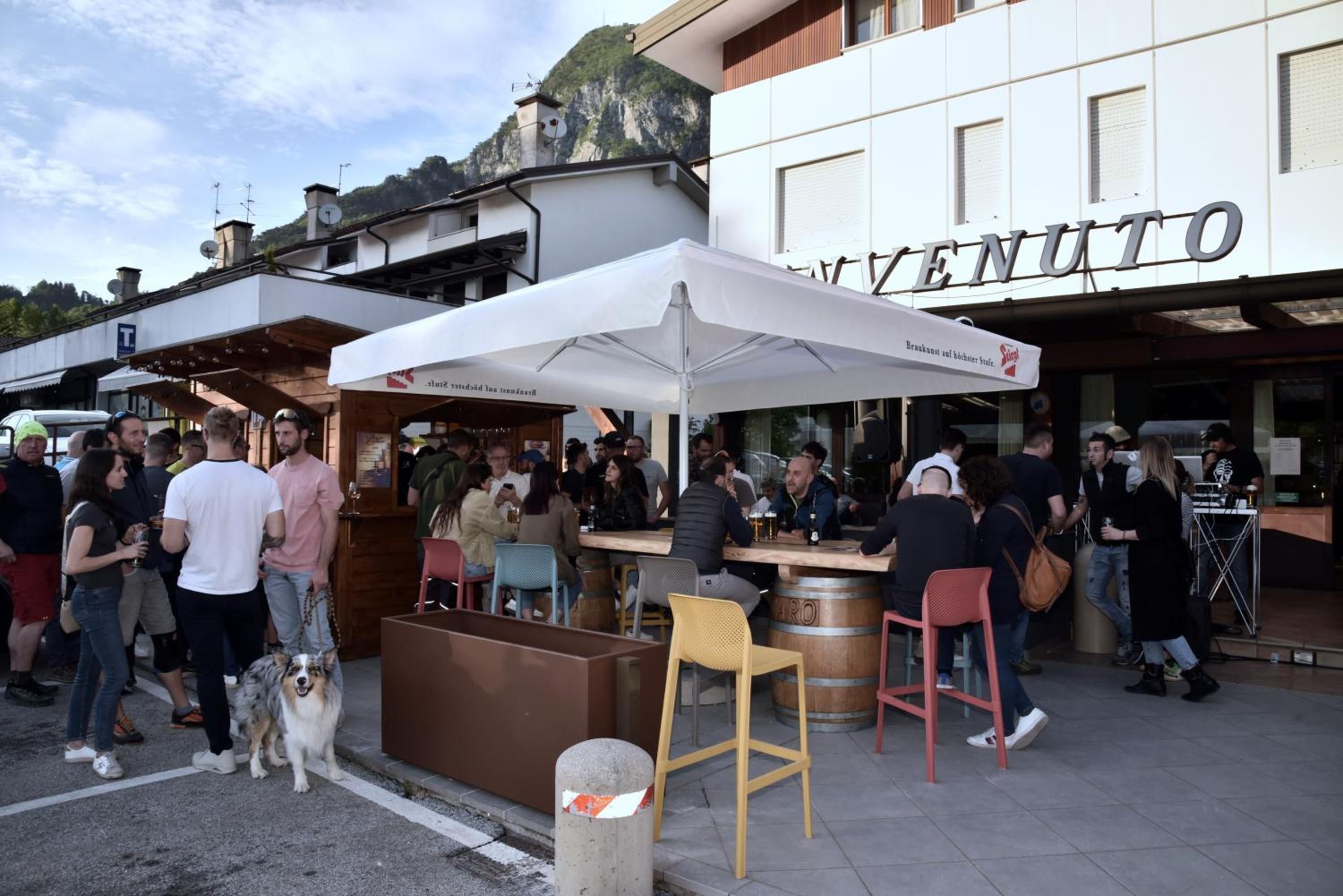Zona exterior amb taules i caires, un gos i persones reunides.
