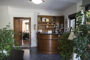 A reception area with a wooden counter, a mirror, and a shelf with various items. - Ristorante Albergo Gerardo Di Masi (Caposele)