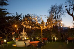 An outdoor dining area with tables and chairs, a fountain, and string lights. - Ristorante Albergo Gerardo Di Masi (Caposele)
