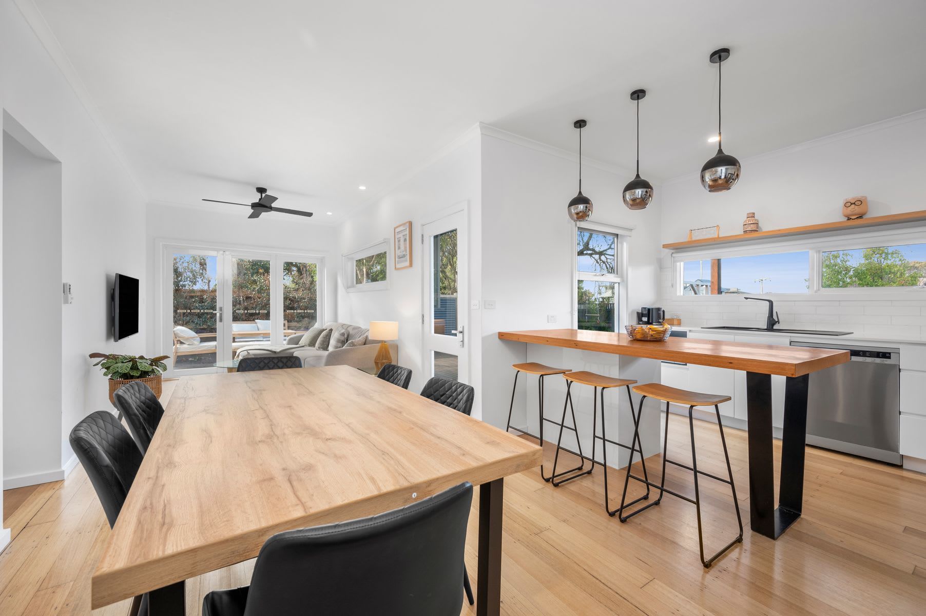 Une cuisine moderne avec un îlot central en bois, des tabourets de bar et des luminaires suspendus.