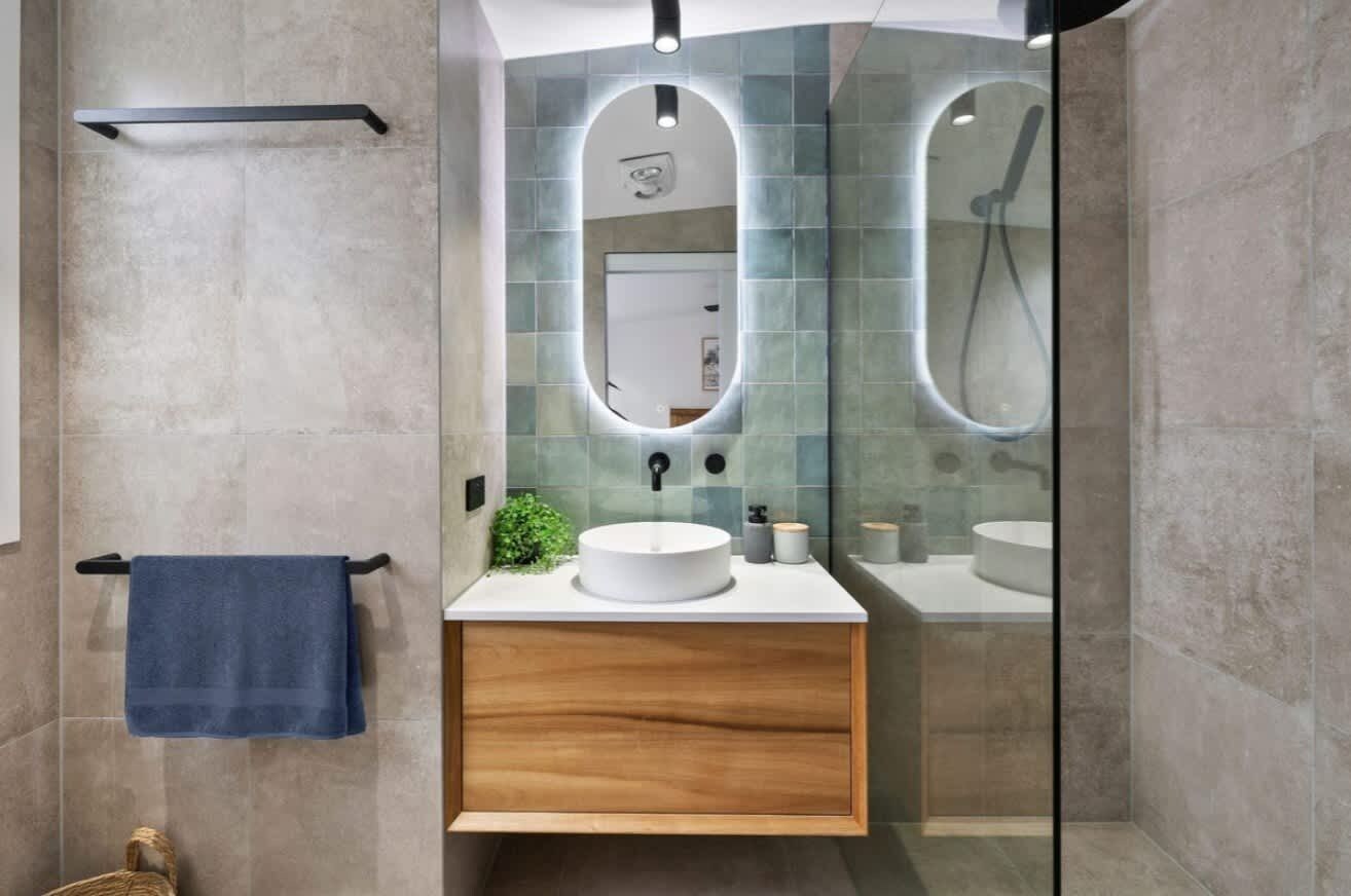 Une salle de bain moderne avec un meuble-lavabo en bois, un lavabo rond et une douche à parois de verre.