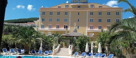 Un hotel con piscina, tumbonas y una estatua.