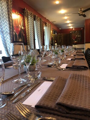 A long dining table set with multiple wine glasses, cutlery, and folded napkins, indicating a formal dining arrangement.