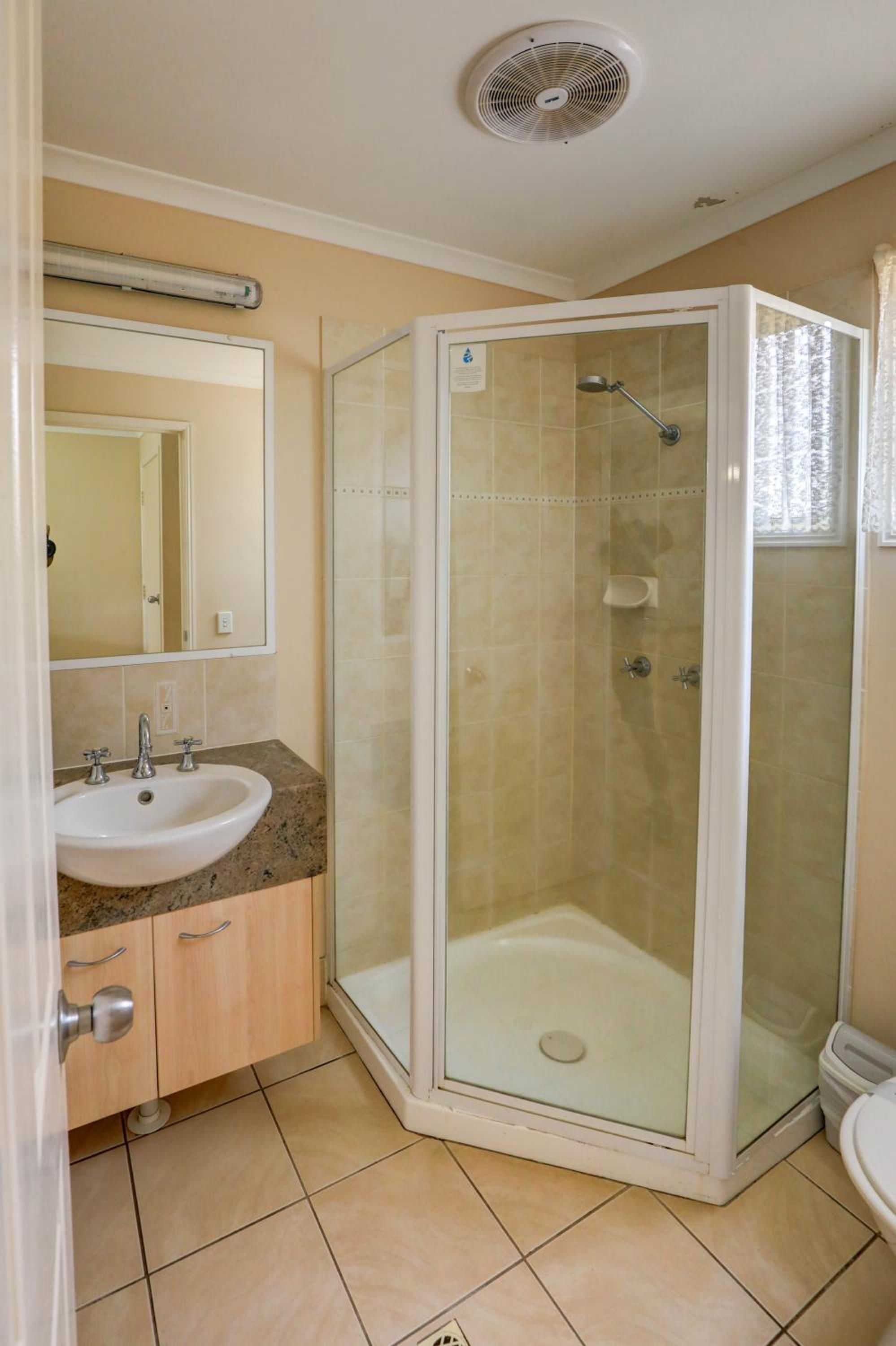 A bathroom with a glass-enclosed shower, a sink with a mirror above it, and a toilet.