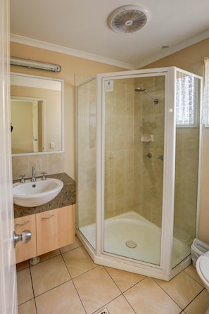A bathroom with a glass-enclosed shower, a sink with a mirror above it, and a toilet.