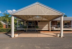 A building with a covered entrance, a brick facade, and a clear sky.