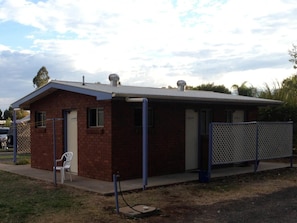 A small brick building with a metal roof, a single door, and a small window.