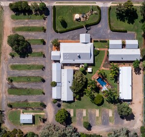 An aerial view of a property with multiple buildings, a swimming pool, and landscaped areas.