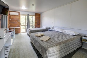 A hotel room with two beds, a desk, and a chair.