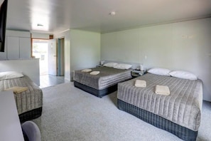 A hotel room with two beds, a kitchenette, and a bathroom.