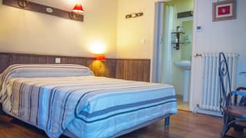 Een slaapkamer met een bed, nachtlampjes, een radiator en een stoel.