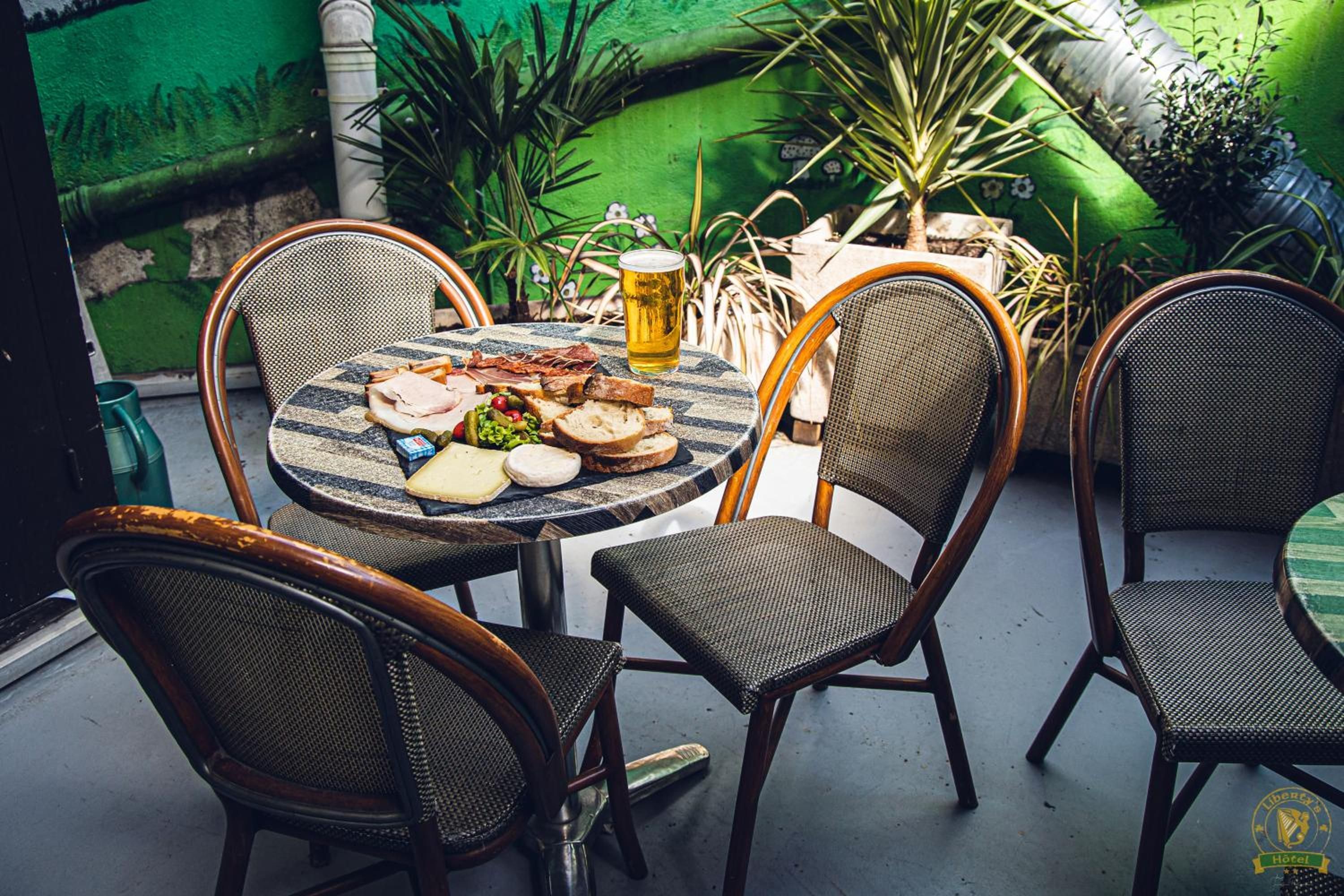 An outdoor dining area with a round table, four chairs, and a glass of beer.