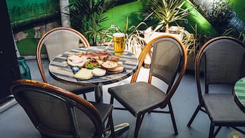 Een terras met een ronde tafel, vier stoelen en een glas bier.