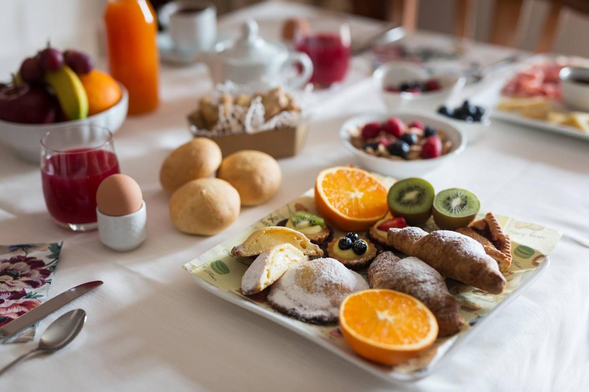 Ein Frühstückstisch mit einer Auswahl an Früchten, Gebäck und einem Saftkrug.