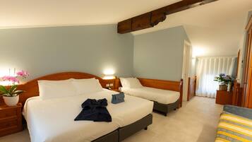 A hotel room with two beds, a wooden headboard, a nightstand, a potted plant, and a view of the corridor.