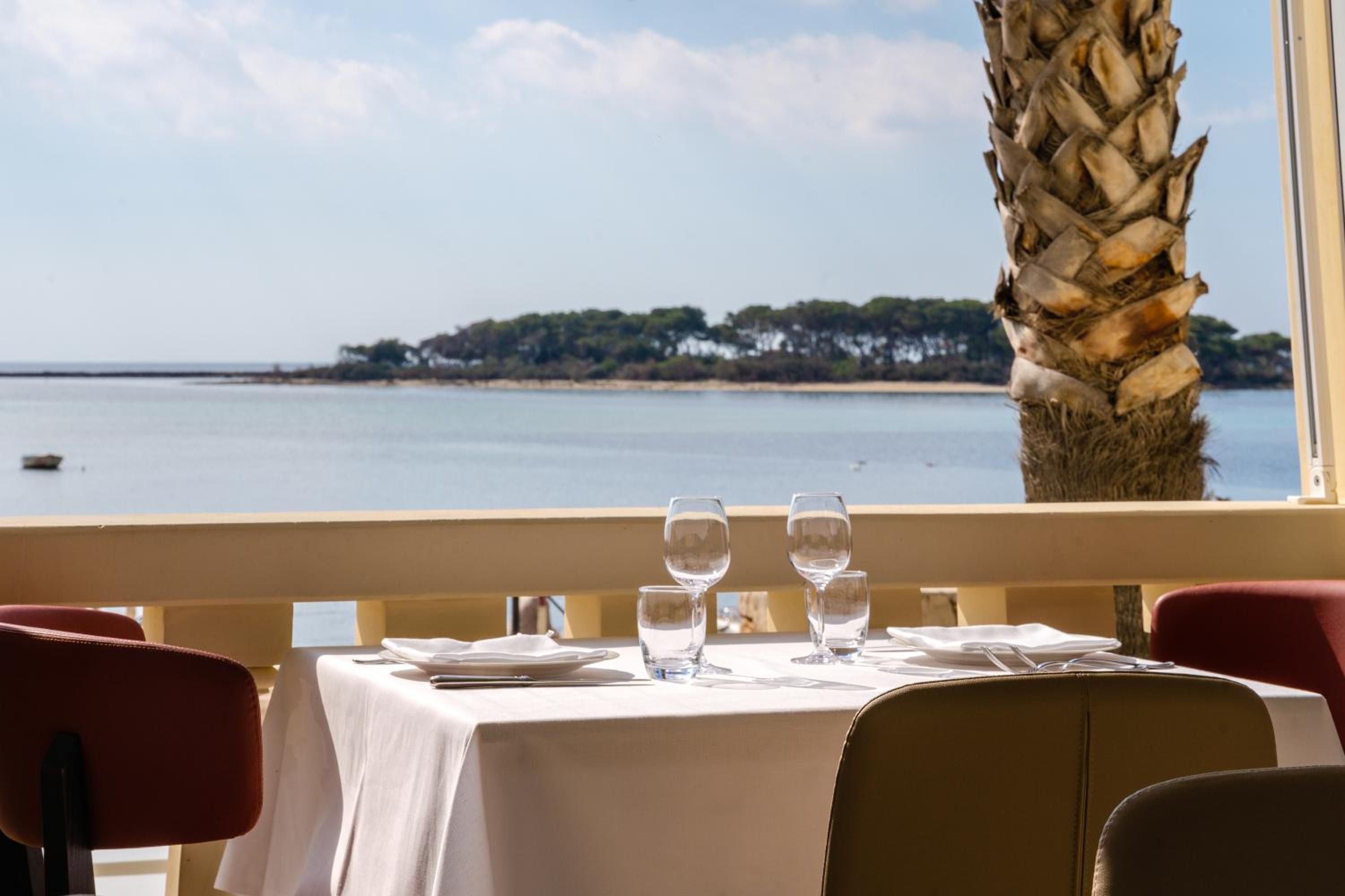 Mesa lista para comer con vista al mar y una isla distante.