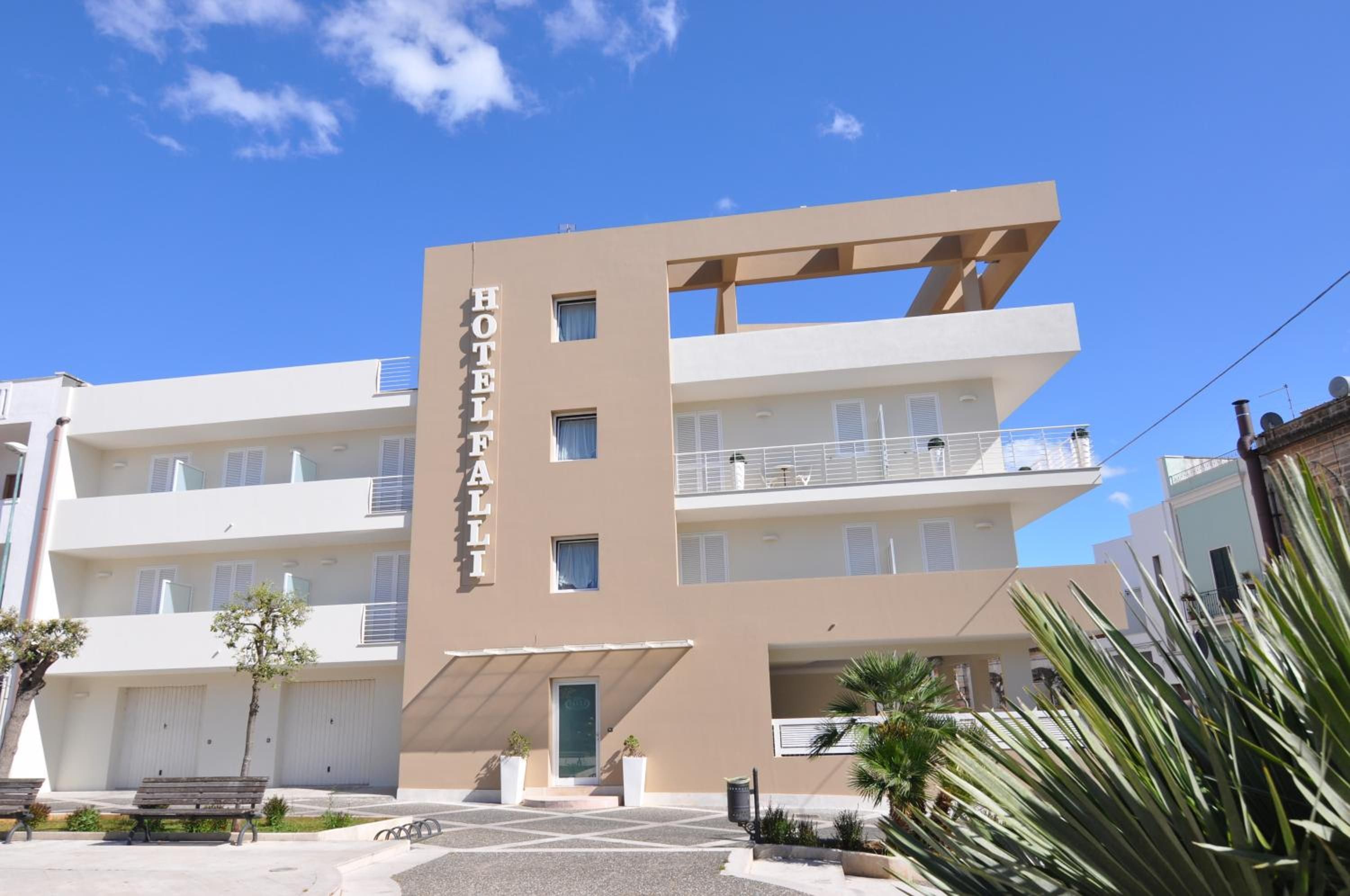 Un hotel moderno de varios pisos, con balcones en cada planta y un cielo despejado.