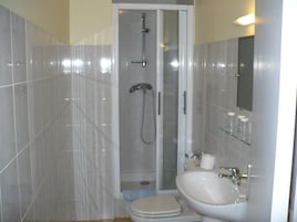 Un baño con ducha, inodoro, lavabo y cabina de ducha de vidrio.