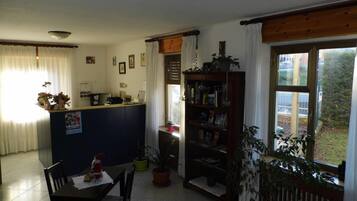 A compact living space with a kitchen area, dining table, and a bookshelf.