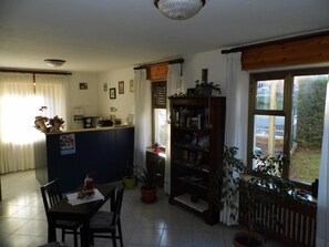 Un espacio habitable compacto con área de cocina, mesa de comedor y estantería.
