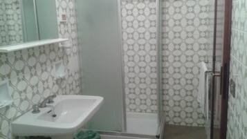 Un bagno con un lavandino bianco, uno specchio e un box doccia con piastrelle decorate.