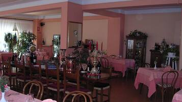 Zona pranzo con diversi tavoli, sedie e vari tipi di tavola apparecchiata.