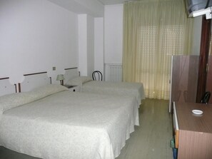 A hotel room with two beds, a desk, a chair, a radiator, and a television. - Albergo Tenda Verde (Falconara Marittima)