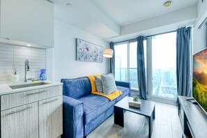 A modern living room with a blue sofa, a coffee table, and a large window with curtains.