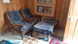 Una habitación con paneles de madera, dos sillones tapizados, una mesita y un cuadro en la pared, además de un alfombra con motivos.
