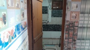 A narrow hallway with a tiled wall on one side and a wooden door on the other.