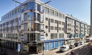 Ein mehrstöckiges Gebäude mit Geschäftsflächen im Erdgeschoss, darunter ein sichtbarer Laden mit Beschilderung.