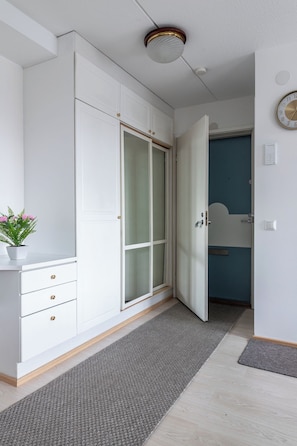 A room with a white wardrobe, a grey rug, and a blue door in the background. - 1BR Downtown Apt with Sauna & Balcony (Lahti)