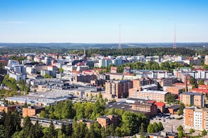 Eine Stadtlandschaft mit einer Mischung aus Geschäfts- und Wohngebäuden, wolkenlosem Himmel und weit entfernten Sendemasten.