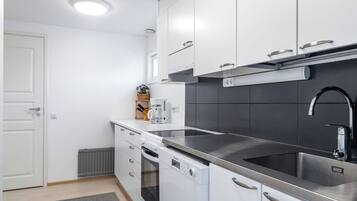 A modern kitchen with white cabinets, a stainless steel sink, and a built-in oven.